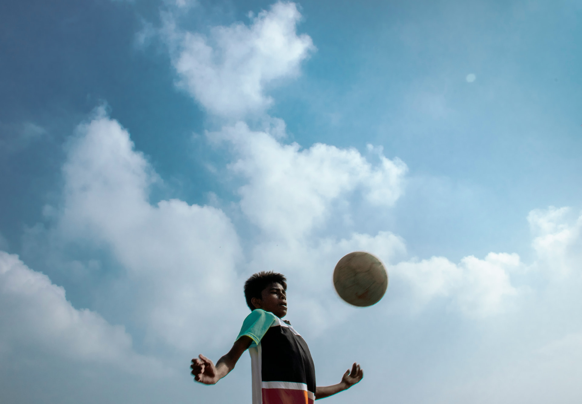 Young player chesting the ball against a bright sky